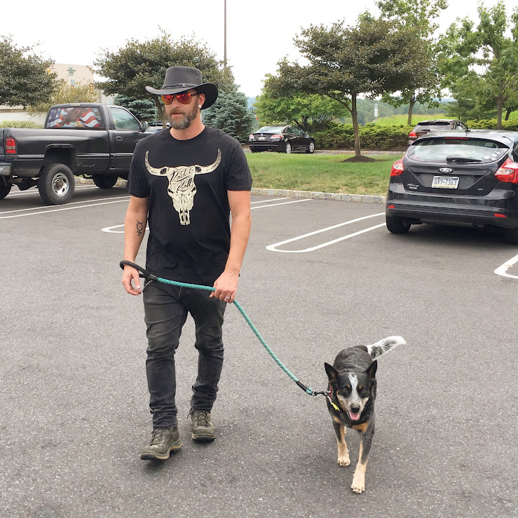Aaron wearing a cowboy hat and walking his dog
