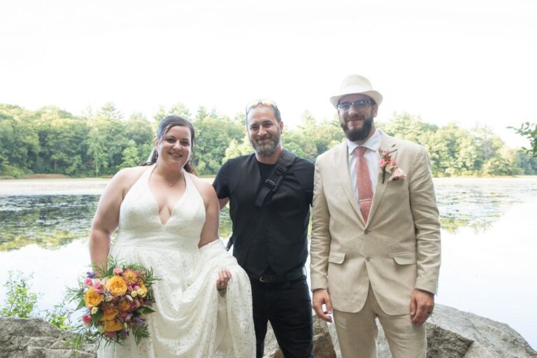 Massachusetts wedding photographer Aaron poses with a bride and a groom in front of a lake after the couple's elopement which he officiated.