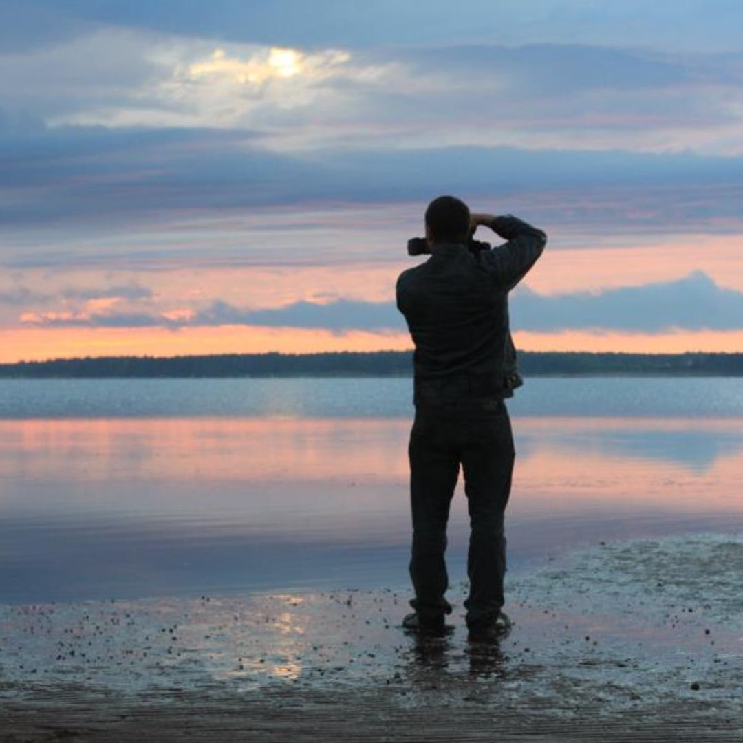 Aaron Spagnolo stands on the shoreline, photographing the Sunset.
