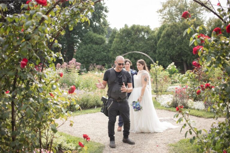Aaron of Spagnolo Photography is instructing two brides on a wedding pose, photographed by his photography partner Nanore during an LGBTQ wedding in Salem, MA.