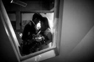 A black and white creative portrait of a bride and groom shot through a small window at a Museum of Science wedding in Boston
