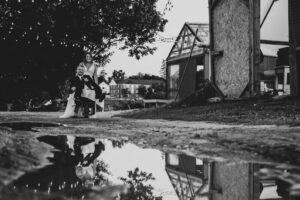 A groom sits in a wheelbarrow that the bride pushes at a Gibbet Hill wedding, photographed in black and white by Spagnolo Photography - the image is featured in the bride's review of the photographers