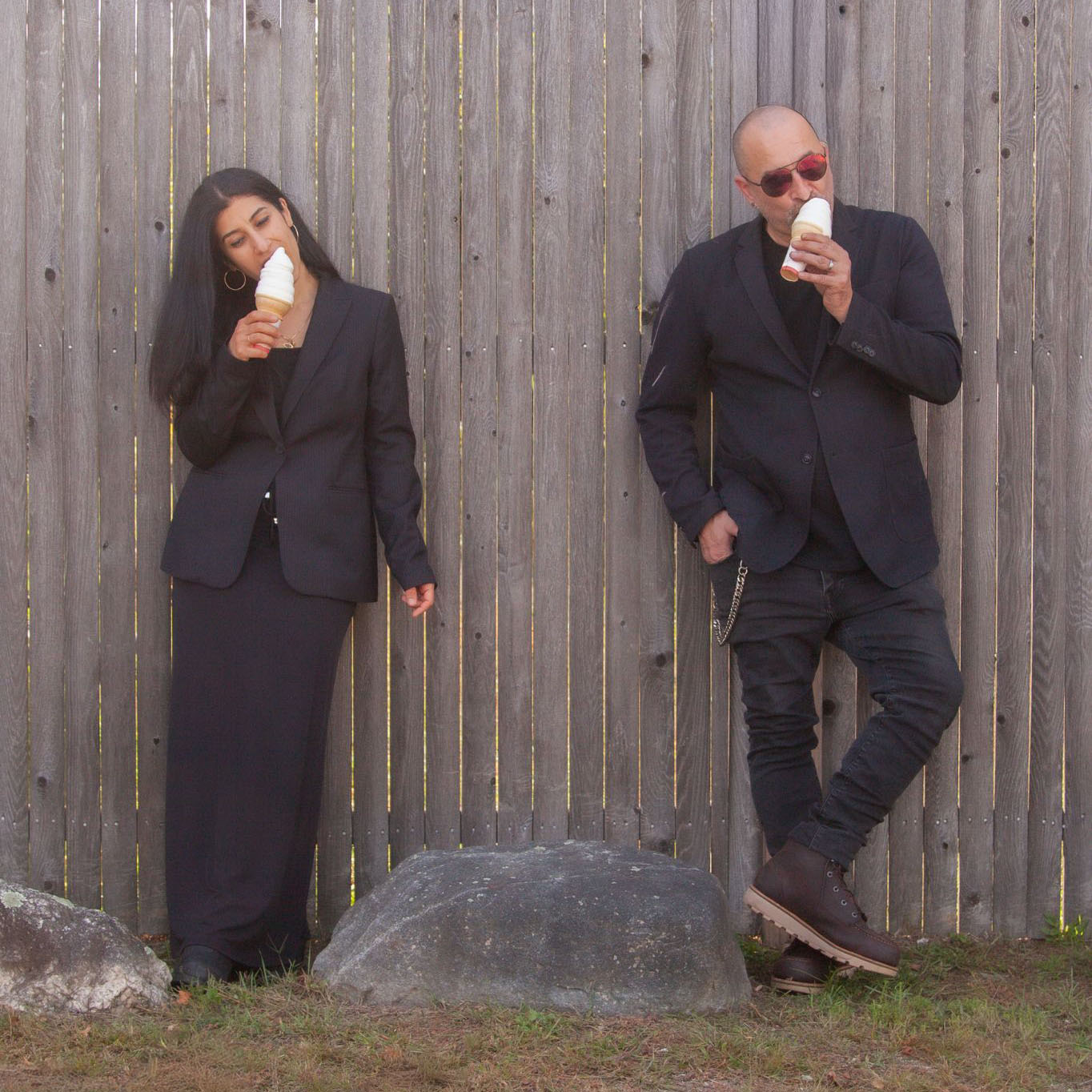 A creative self portrait of Boston wedding photographers Aaron and Nanore of Spagnolo Photography eating ice cream while leaning against a fence