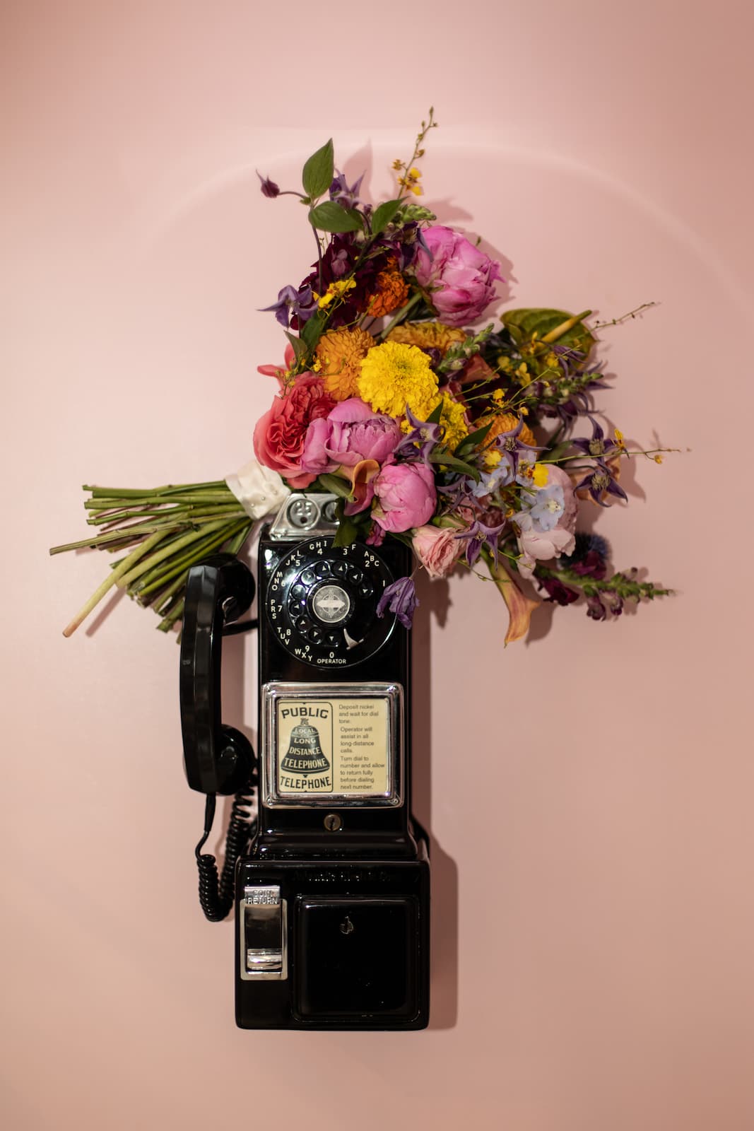 A bridal bouquet rests on top of the Langham Boston’s vintage pink telephone, captured by Spagnolo Photography.