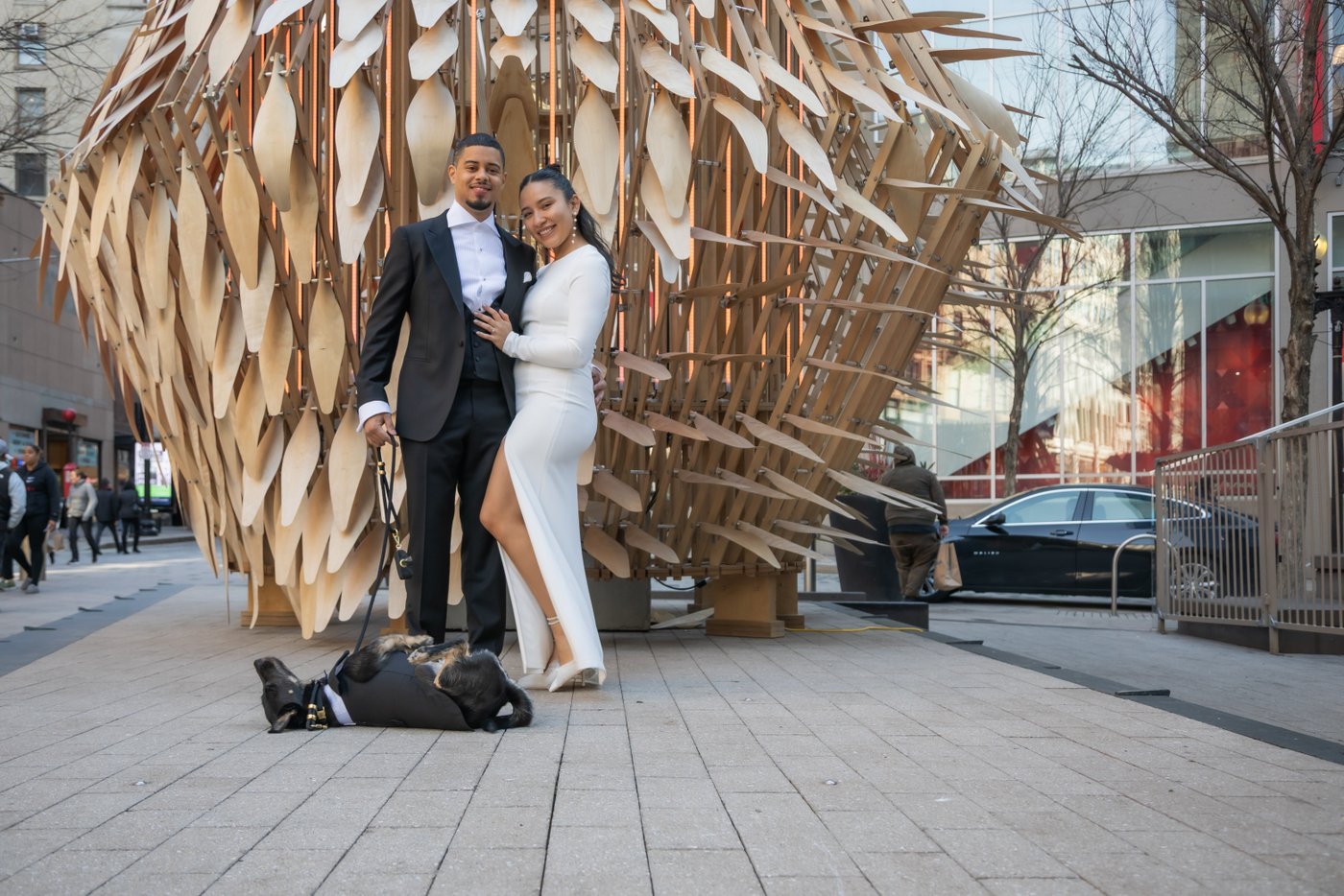Bride and groom pose by a sculpture on their way to elope at Boston City Hall