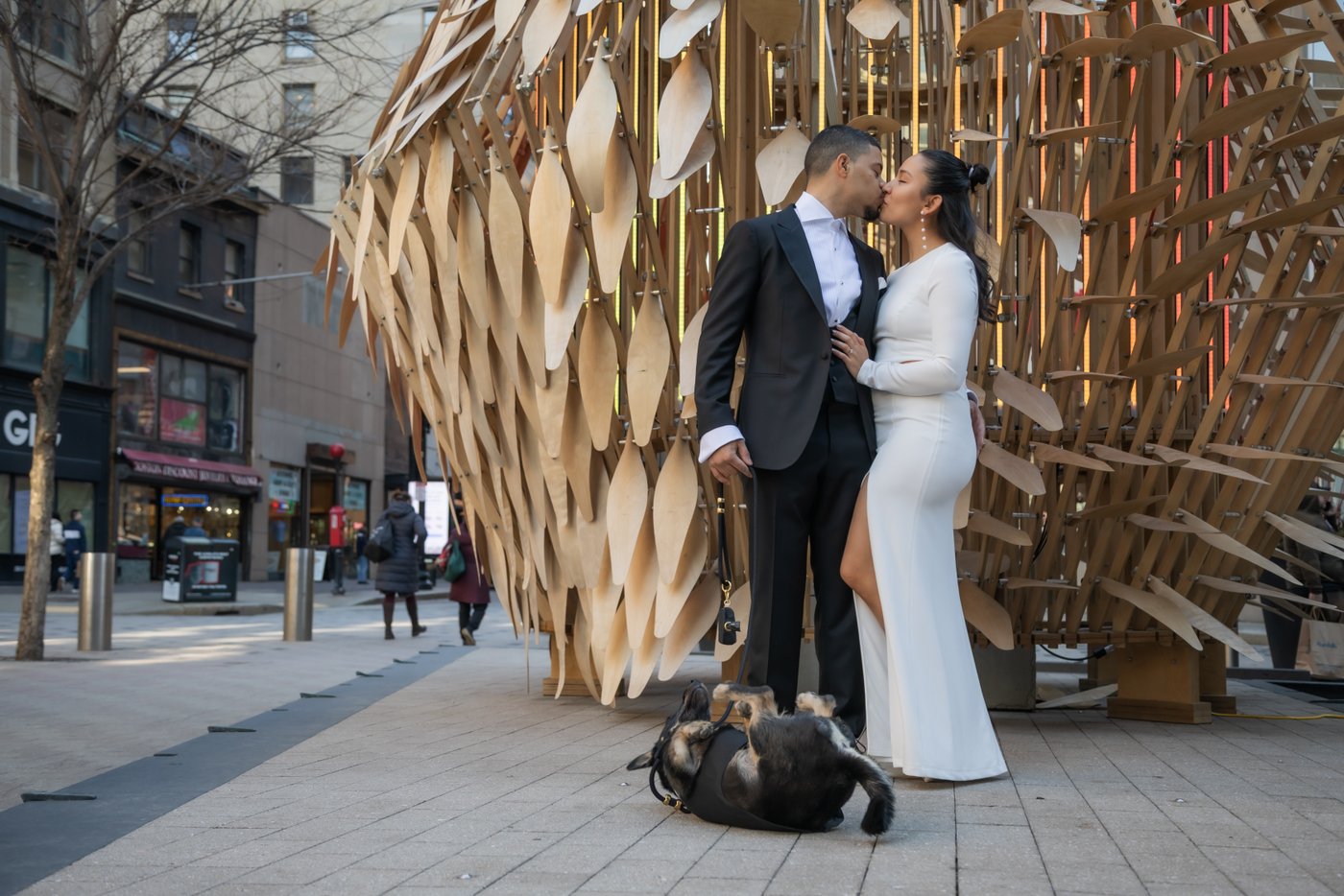 Bride and groom kiss by a sculpture on their way to elope at Boston City Hall