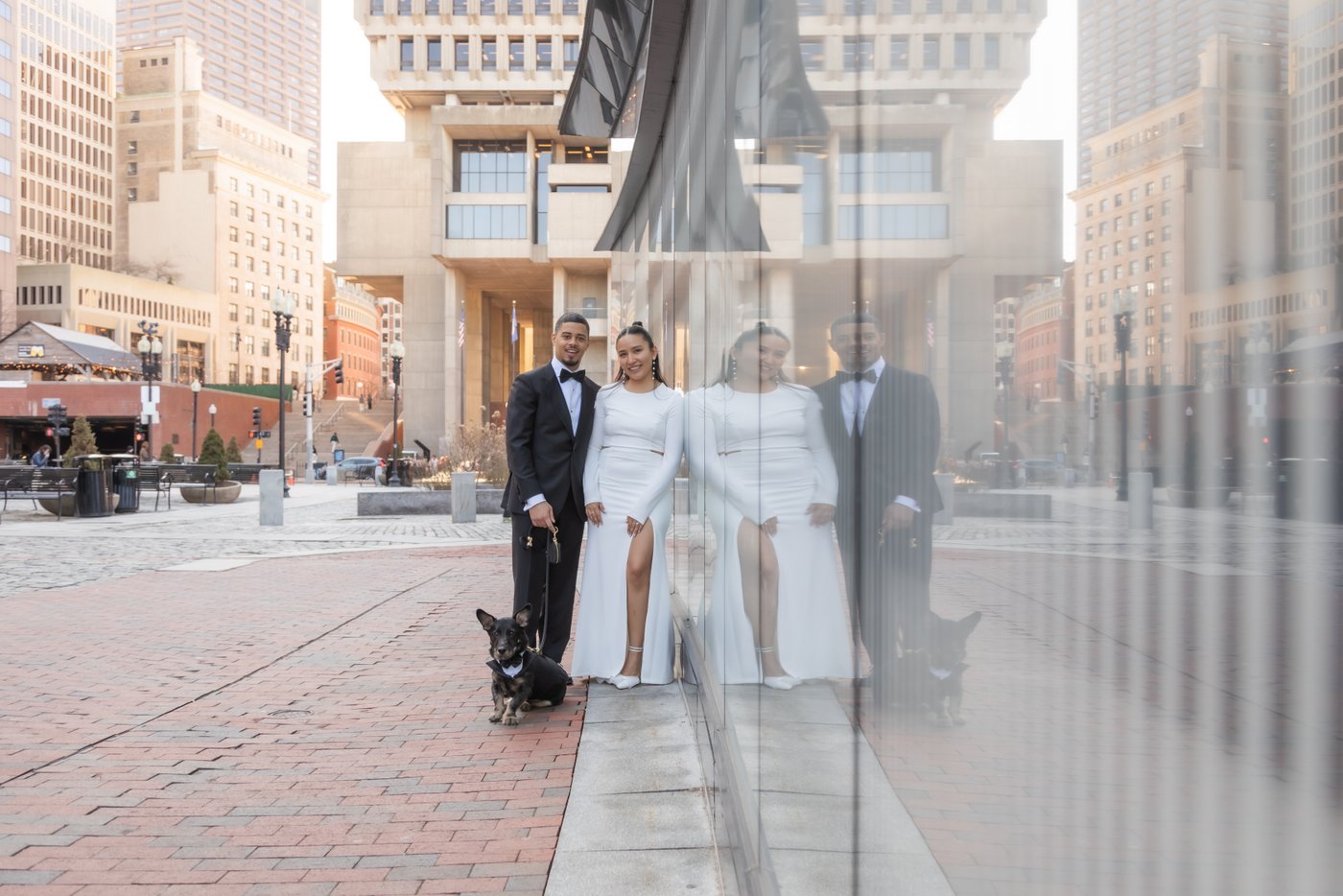 Bride and groom posing against the glass wall of a building in Boston after getting married at Boston City Hall