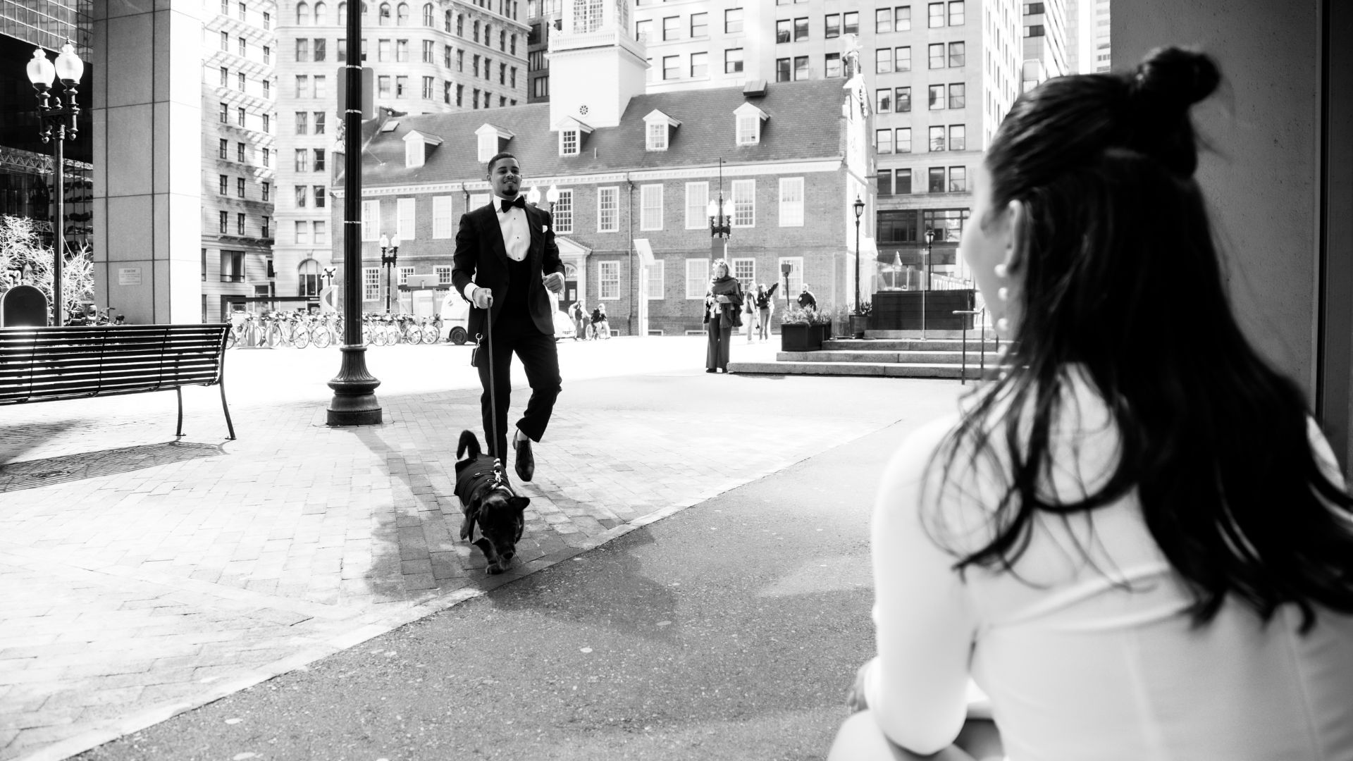 The bride watches the groom walking toward her with their dog, on their way to Boston City Hall to get married