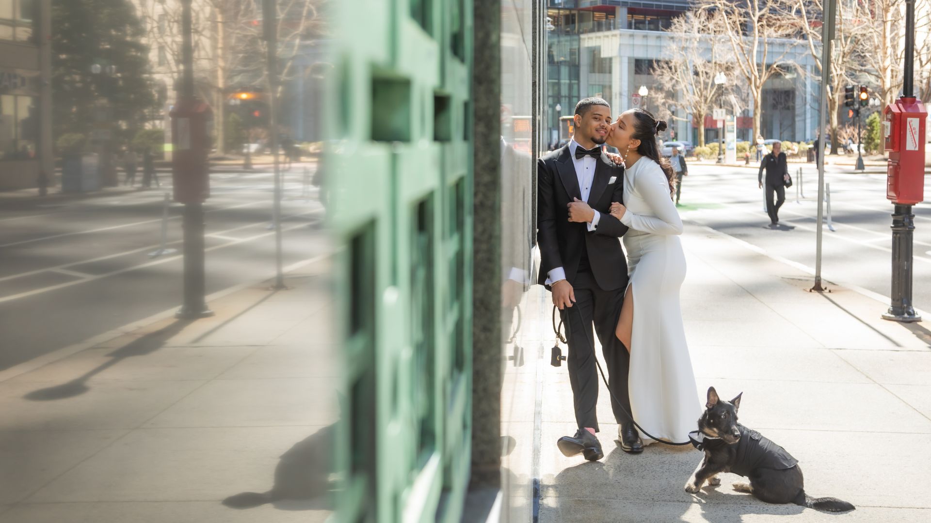 The bride and groom pose for a shot with their dog on their walk to Boston City Hall for their wedding