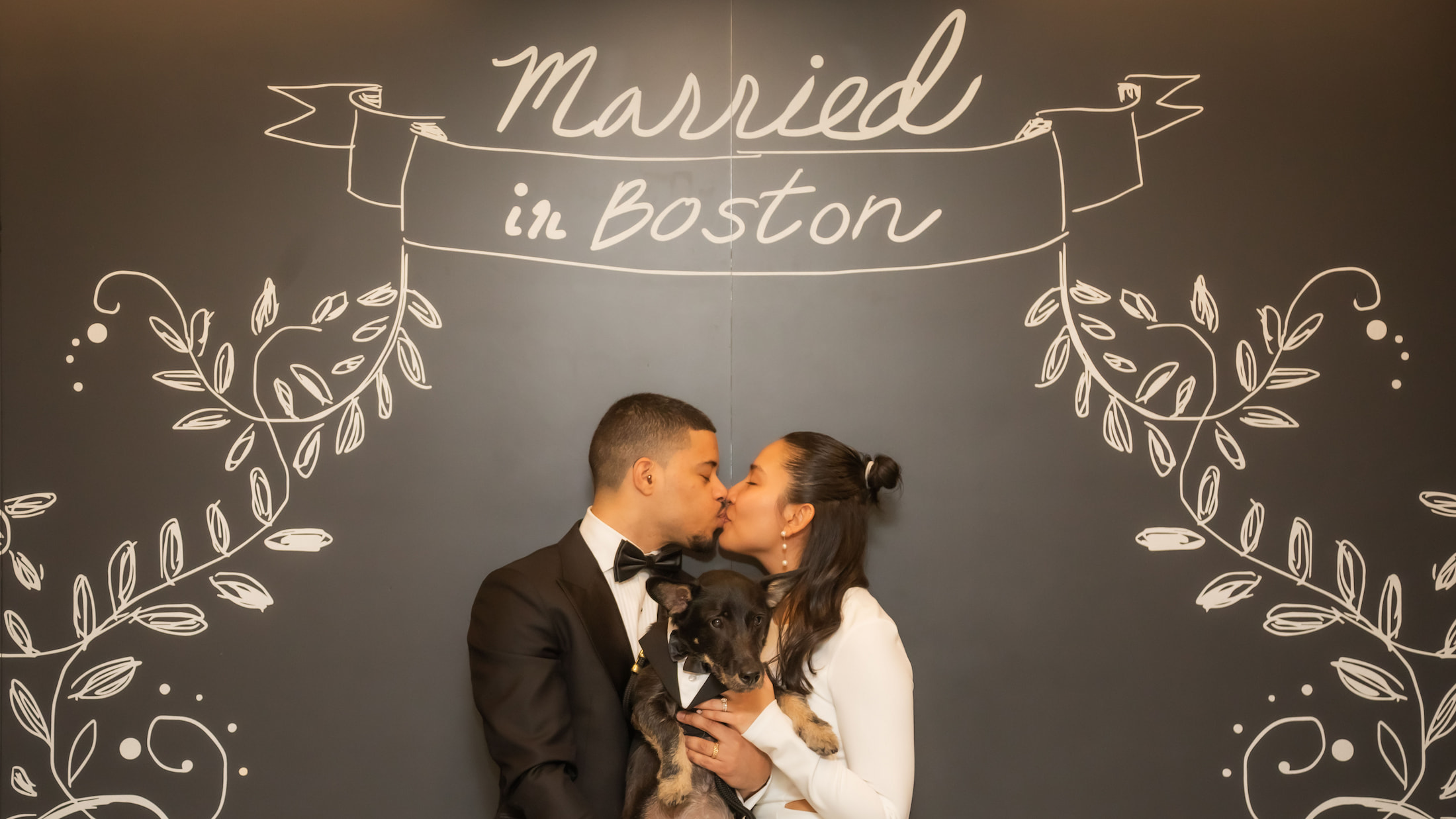 Boston City Hall wedding photographers Spagnolo Photography capturing a bride and a groom kissing under the "Married in Boston" sign following their Boston City Hall elopement.