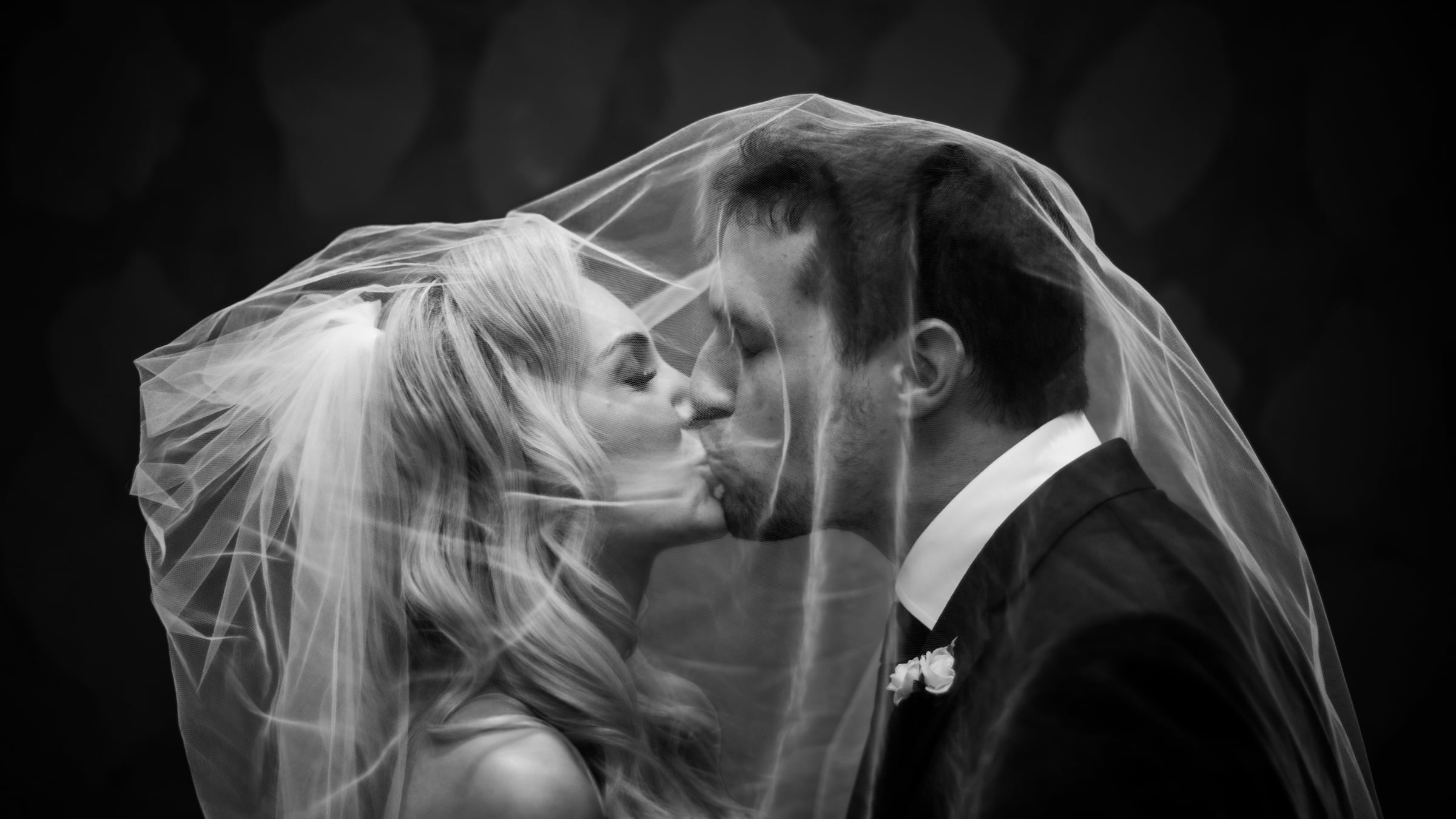 Boston wedding photographers Spagnolo Photography capturing a dramatic and artistic black and white photo of a bride and a groom kissing under a veil at a Boston Harbor Hotel wedding.