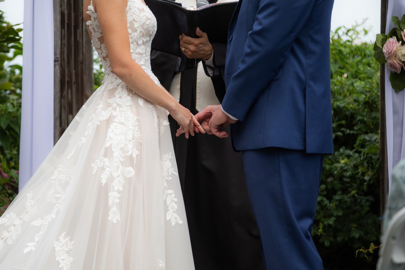 A close up of the bride's and groom's hands touching during their Hammond Castle wedding ceremony