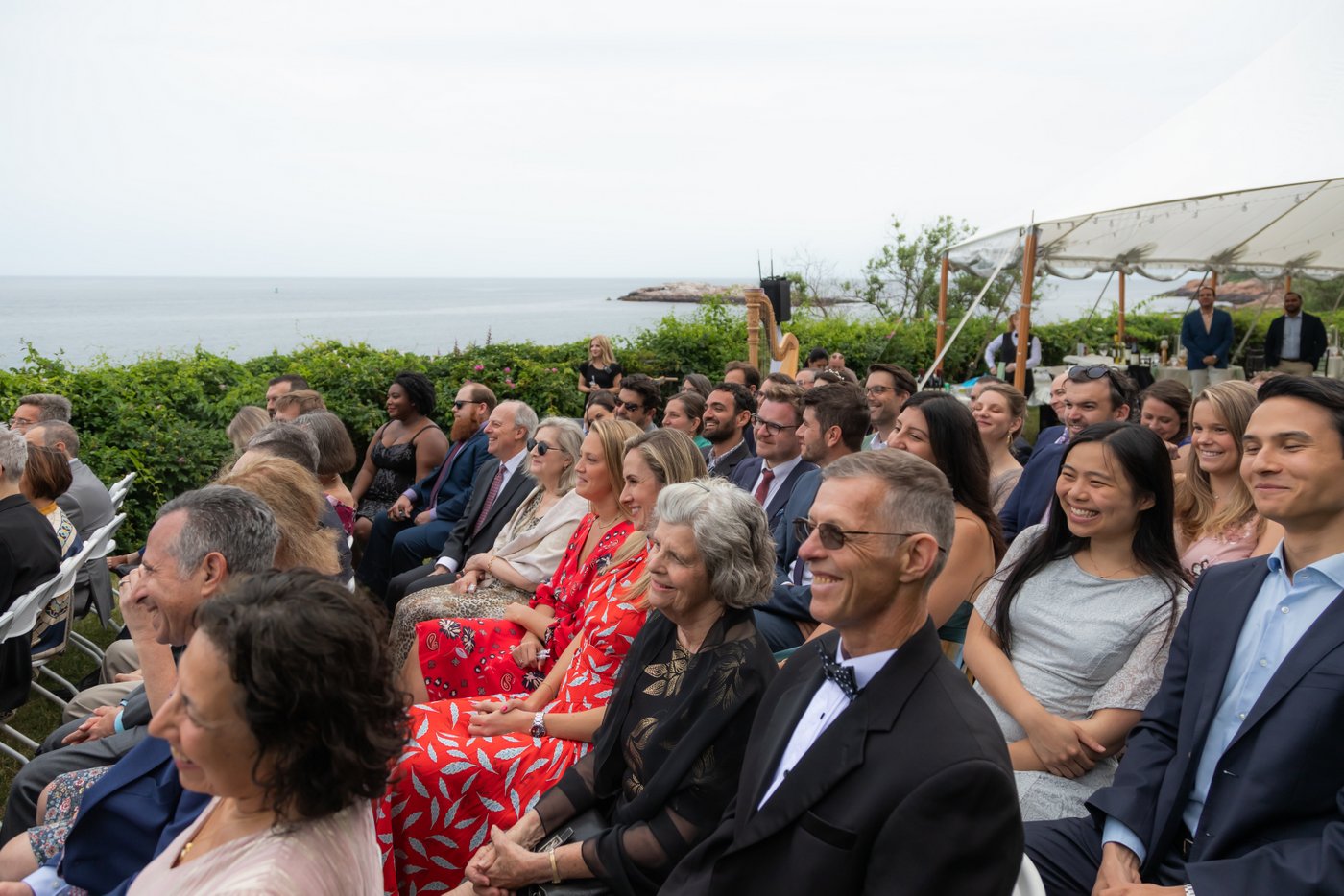 A shot of the guests watching the wedding ceremony on the oceanside lawn of Hammond Castle
