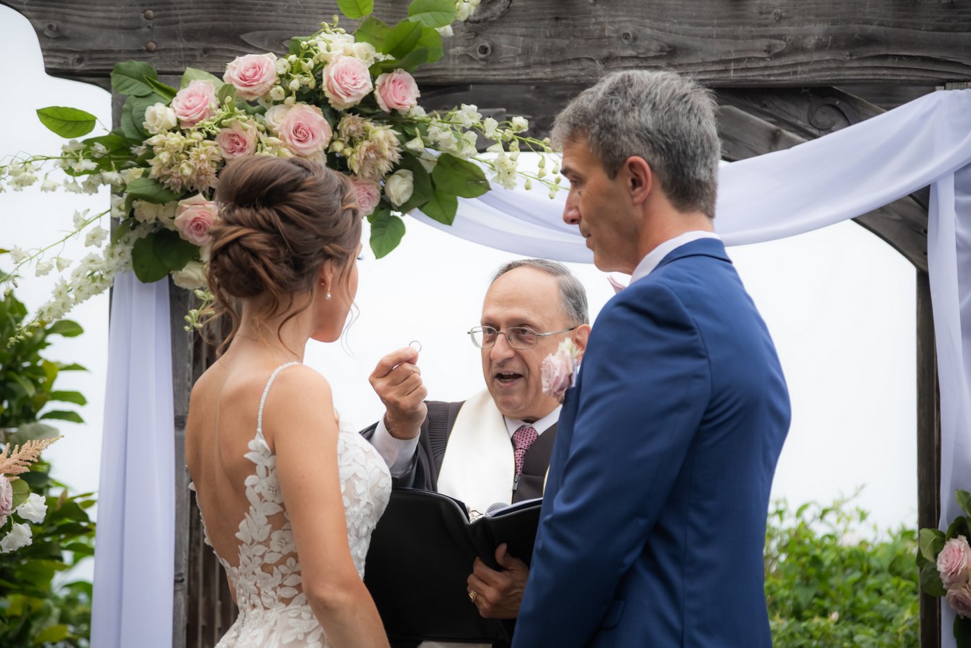 The officiant directs his words to the bride while holding the wedding band during a Hammond Castle wedding ceremony