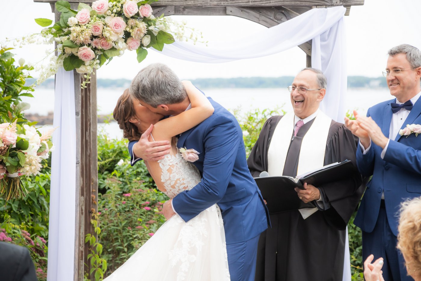 The bride and groom share their first kiss at the altar overlooking the ocean at a Hammond Castle wedding ceremony
