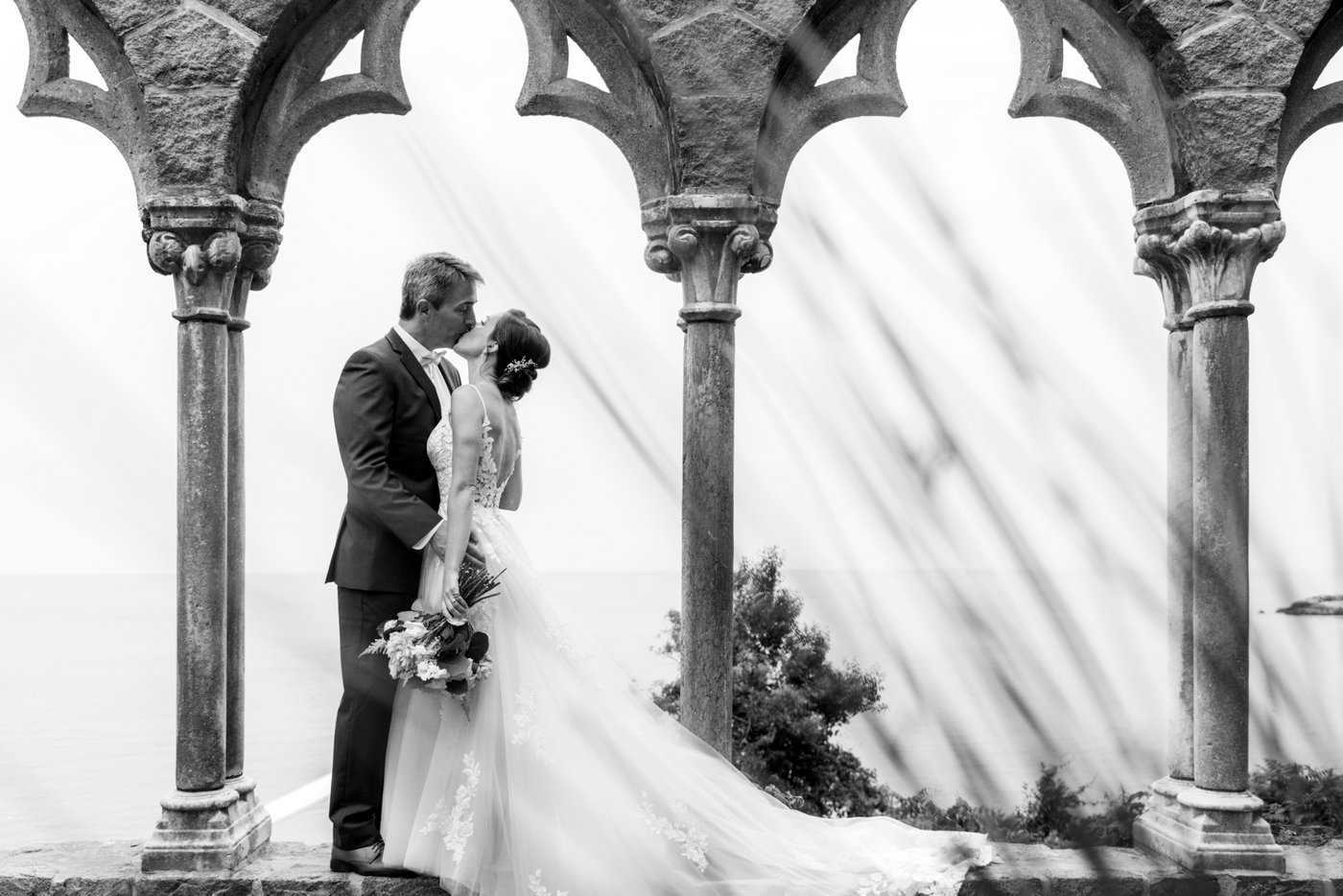 Portrait of the couple framed by stone arches during their Hammond Castle wedding.
