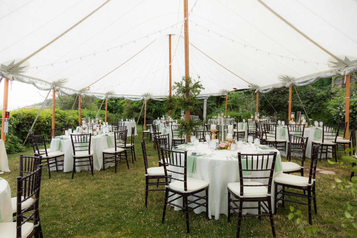 White linen and beautiful greenery decorating the tent at a Hammond Castle wedding in Gloucester, MA
