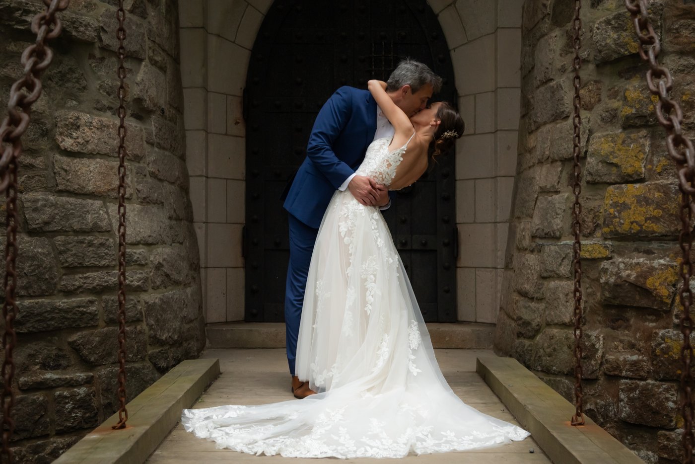 A romantic shot of the groom dipping and kissing the bride on the Hammond Castle drawbridge, before their tented wedding reception on the castle's oceanside lawn
