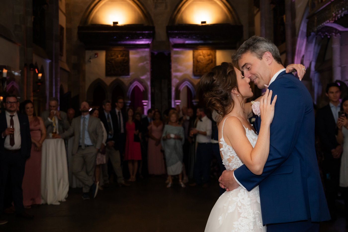 A romantic moment between the bride and groom during their first dance in the Great Hall of Hammond Castle during their wedding reception
