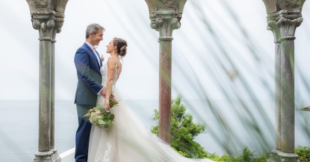 Following their wedding ceremony, a bride and a groom have a moment by the stone arches at Hammond Castle Museum in Gloucester.