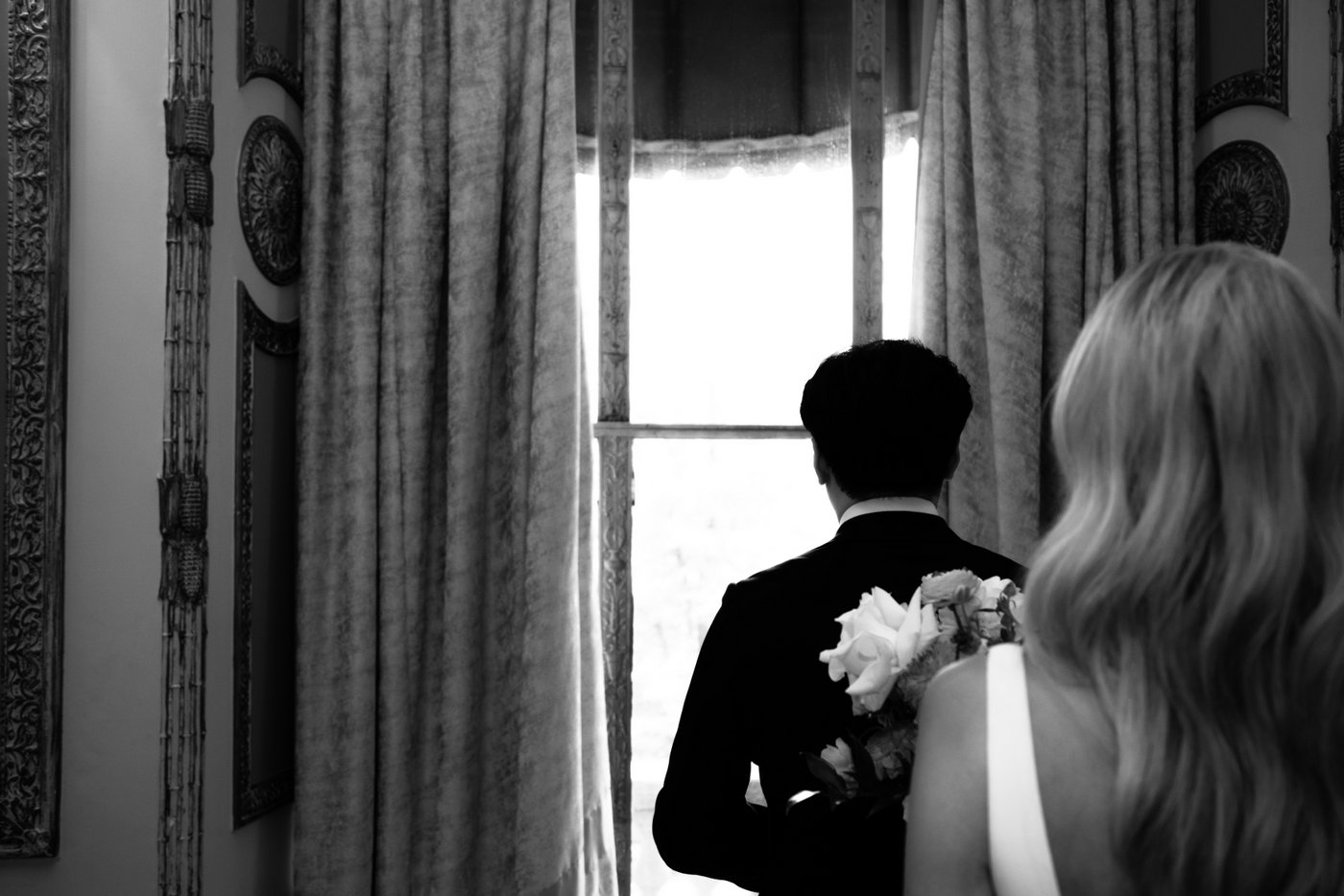 A black and white photo of the bride approaching the groom for their first look at the Langham Hotel in Boston.