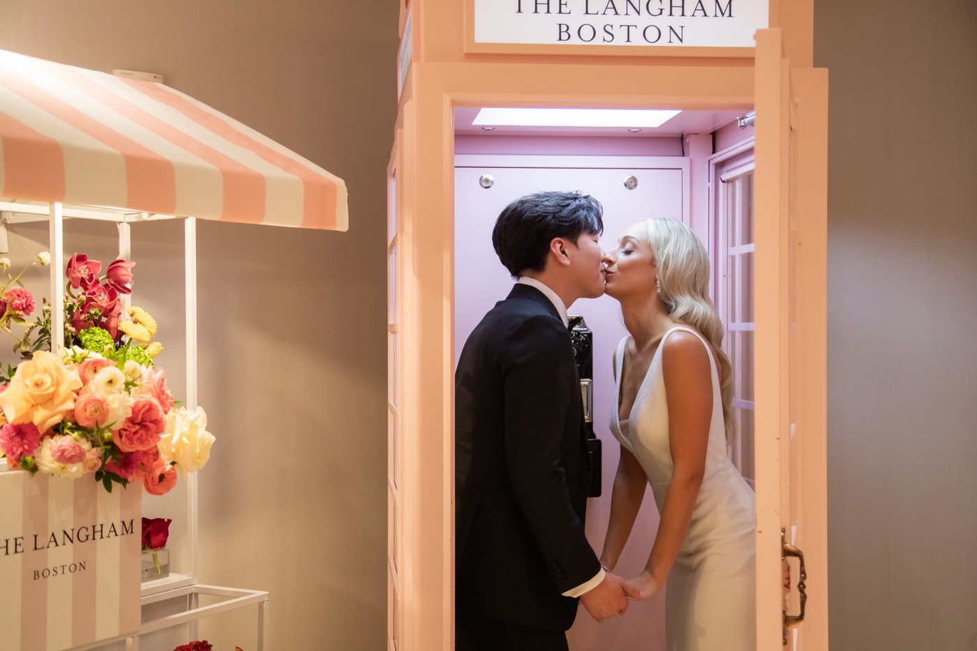 A bride and a groom kiss inside the iconic pink phone booth at the Langham Hotel in Boston following their First Look on their wedding day, before heading to the State Room in Boston.