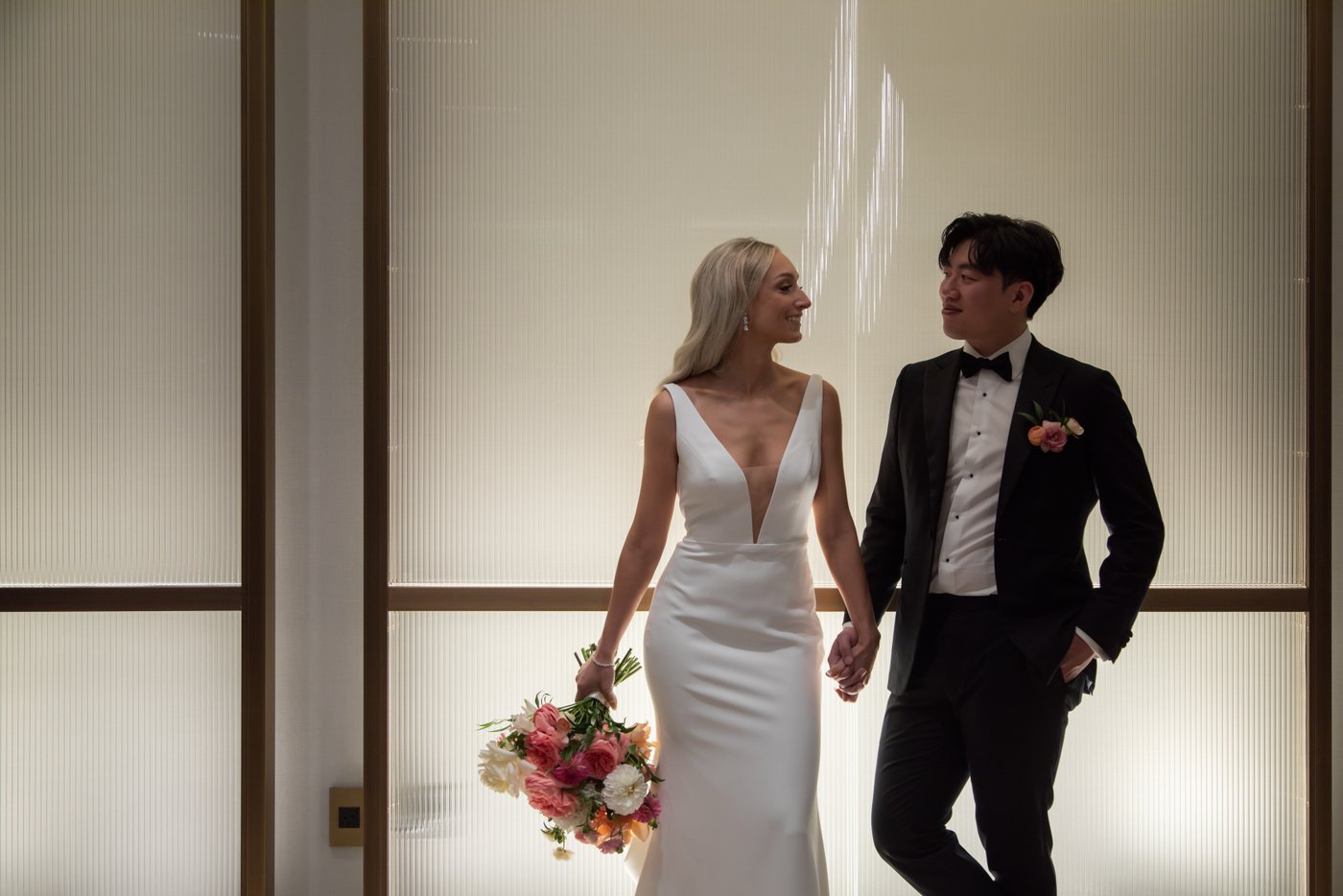 A portrait of the bride and groom holding hands and looking at each other at the Langham Hotel in Boston, shot by creative Boston wedding photographers