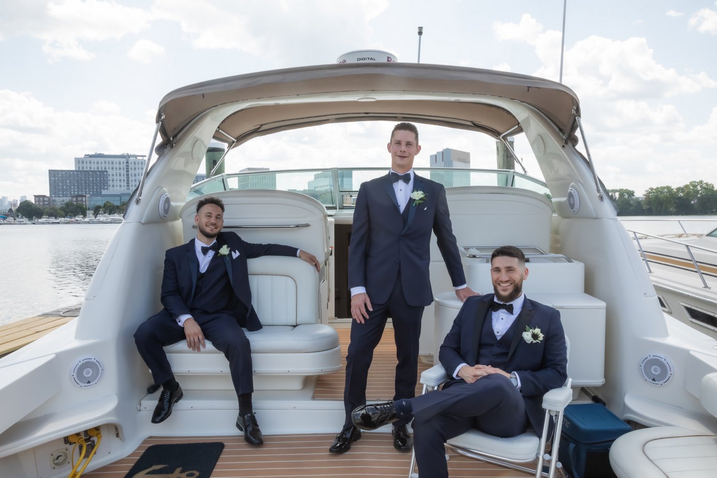 Groom and groomsmen pose on a docked boat on the Mystic River for wedding portraits in Medford, Massachusetts.