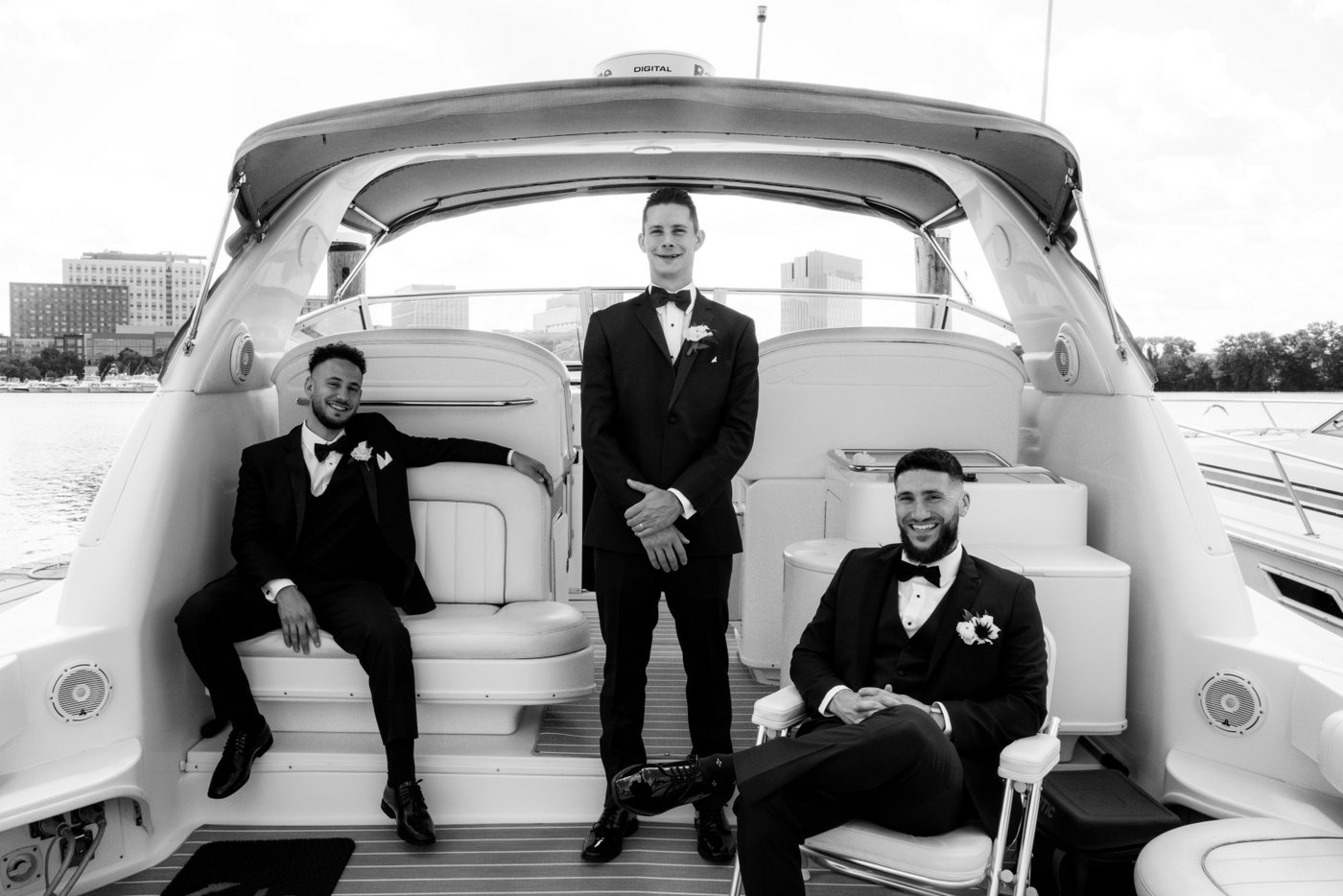 Groom and groomsmen pose for relaxed wedding portraits on a docked boat on the Mystic River in Medford, MA, near Station Landing, before heading to Oceanview of Nahant for the wedding.