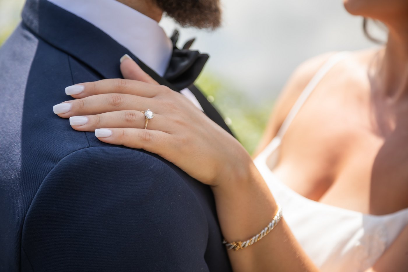 A close-up shot of the bride's hand on the groom's shoulder during their first look