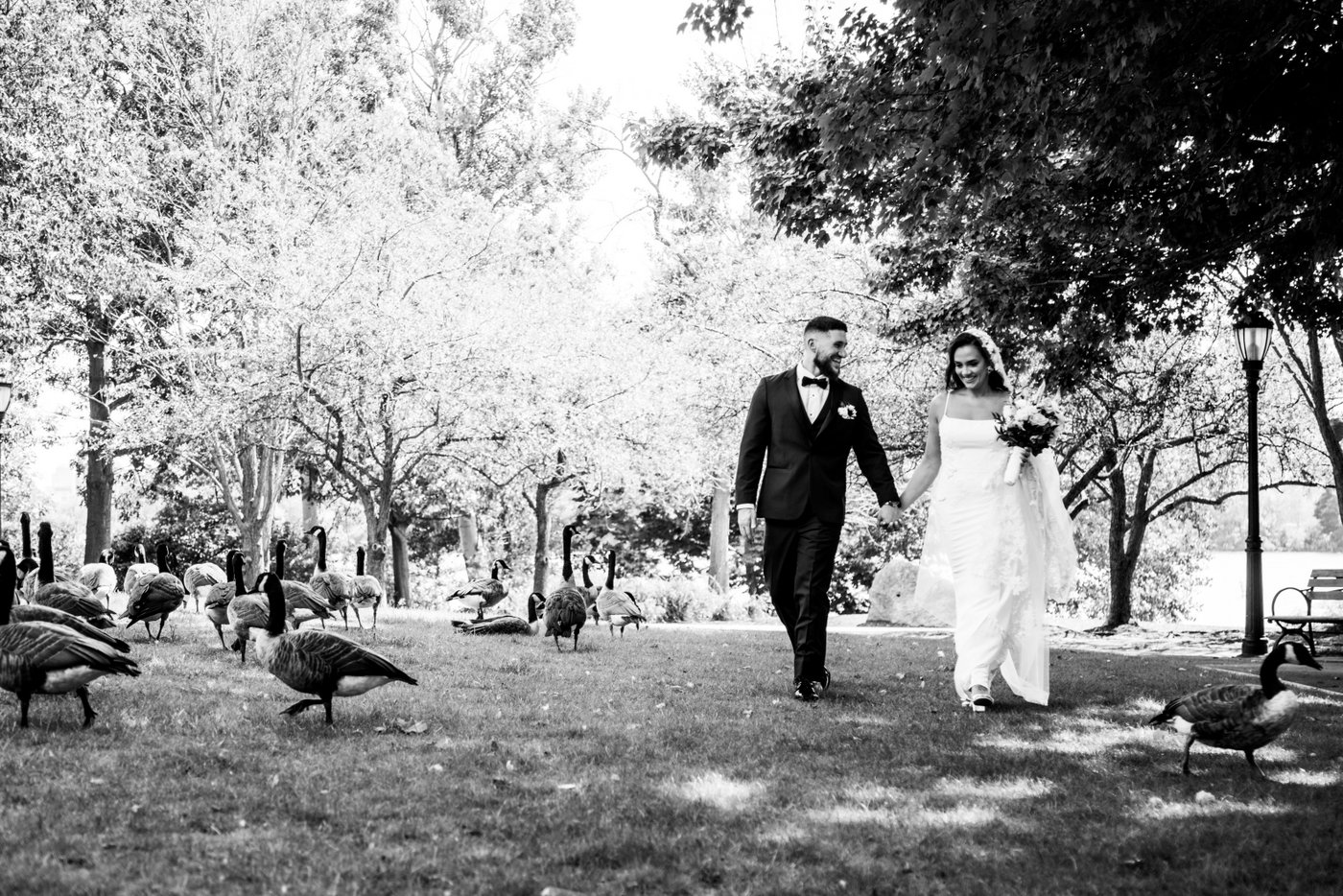 The bride and groom walking hand-in-hand in the park before their Oceanview of Nahant wedding