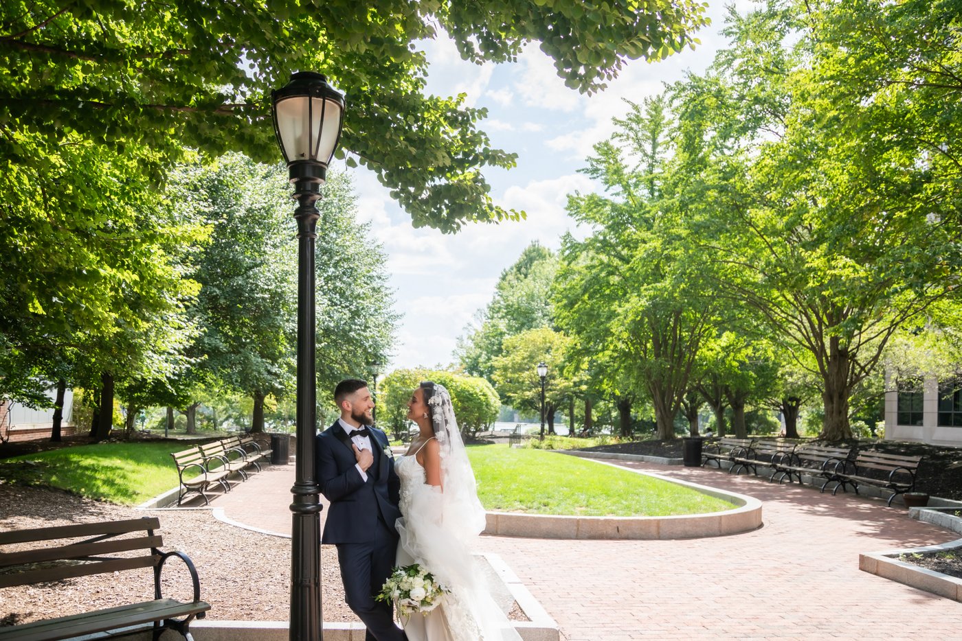 The bride and groom lean against a lamp post in Station Landing Park