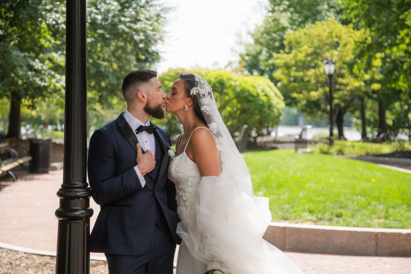 The bride and groom kiss by the lamp post after their First Look in Station Landing Park