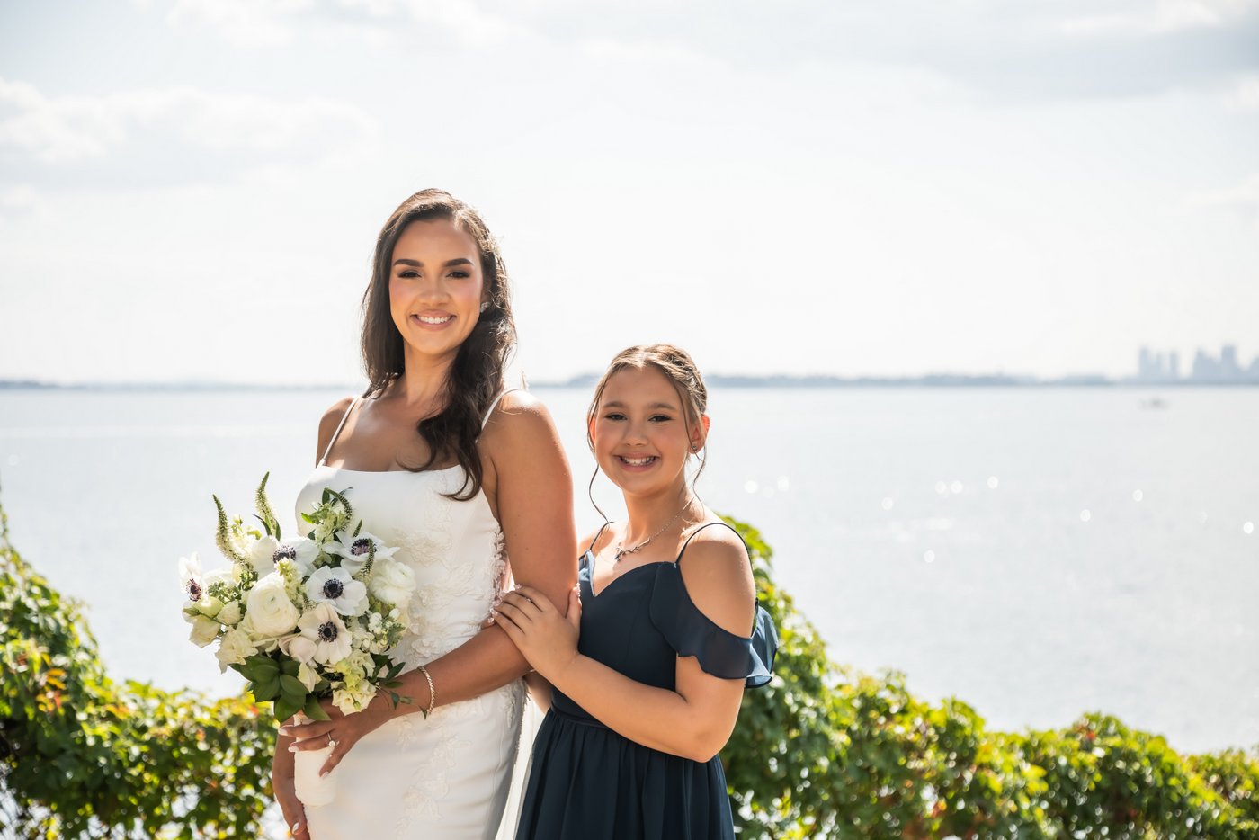 Portrait of the bride with her daughter with the ocean behind them