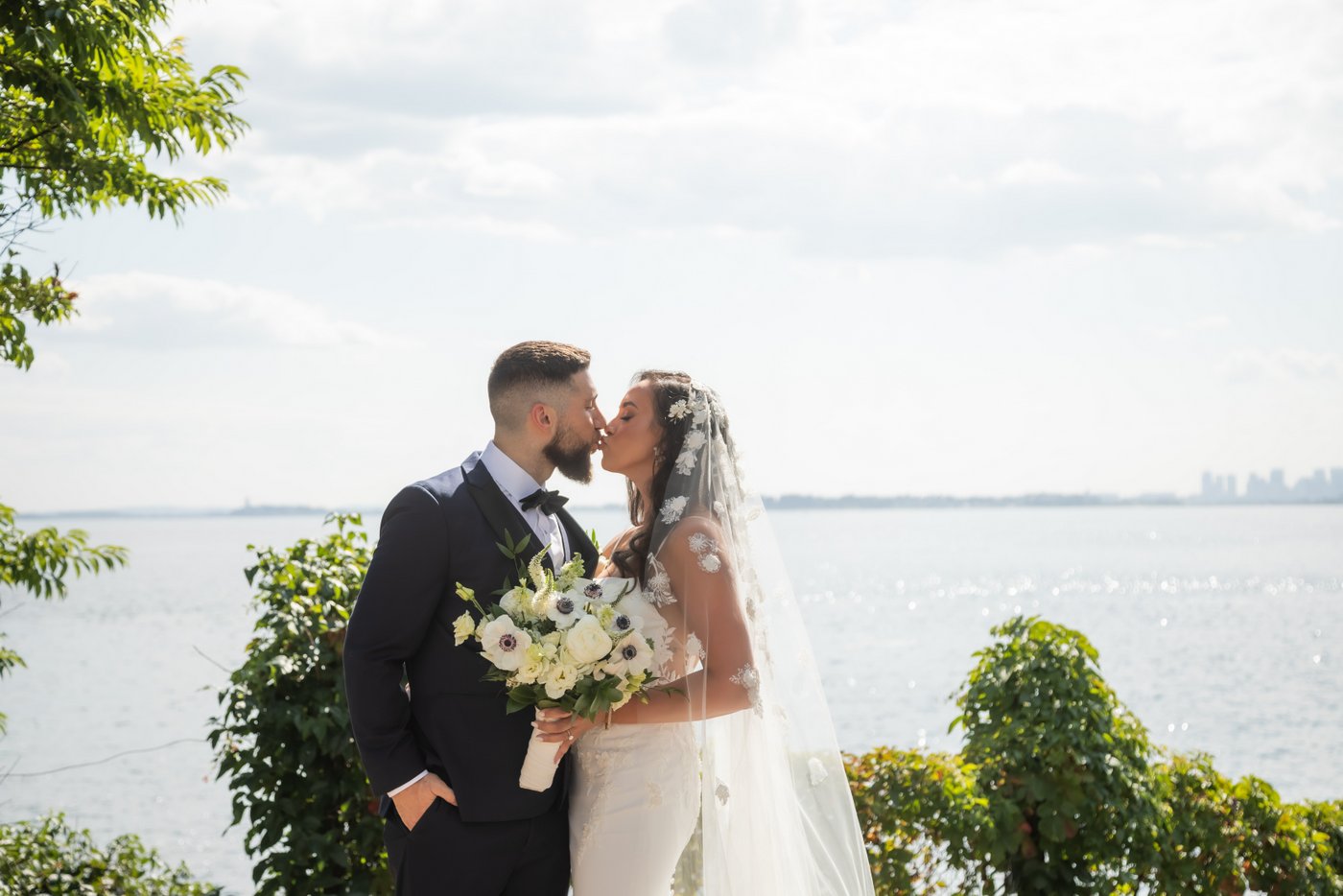 Bride and groom kiss in front of the ocean during their Oceanview Nahant wedding