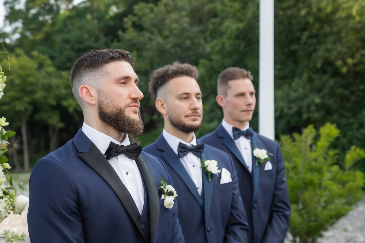 The groom stands at the altar, next to him the groomsmen, as the doors open and the bride appears during an Oceanview of Nahant beach wedding ceremony in Massachusetts.