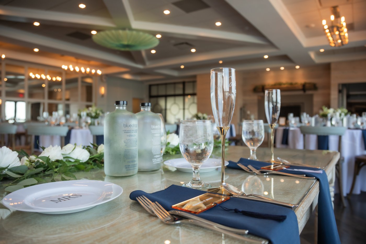 The table setting with navy napkins and champagne flutes on the sweetheart table at the Oceanview of Nahant wedding
