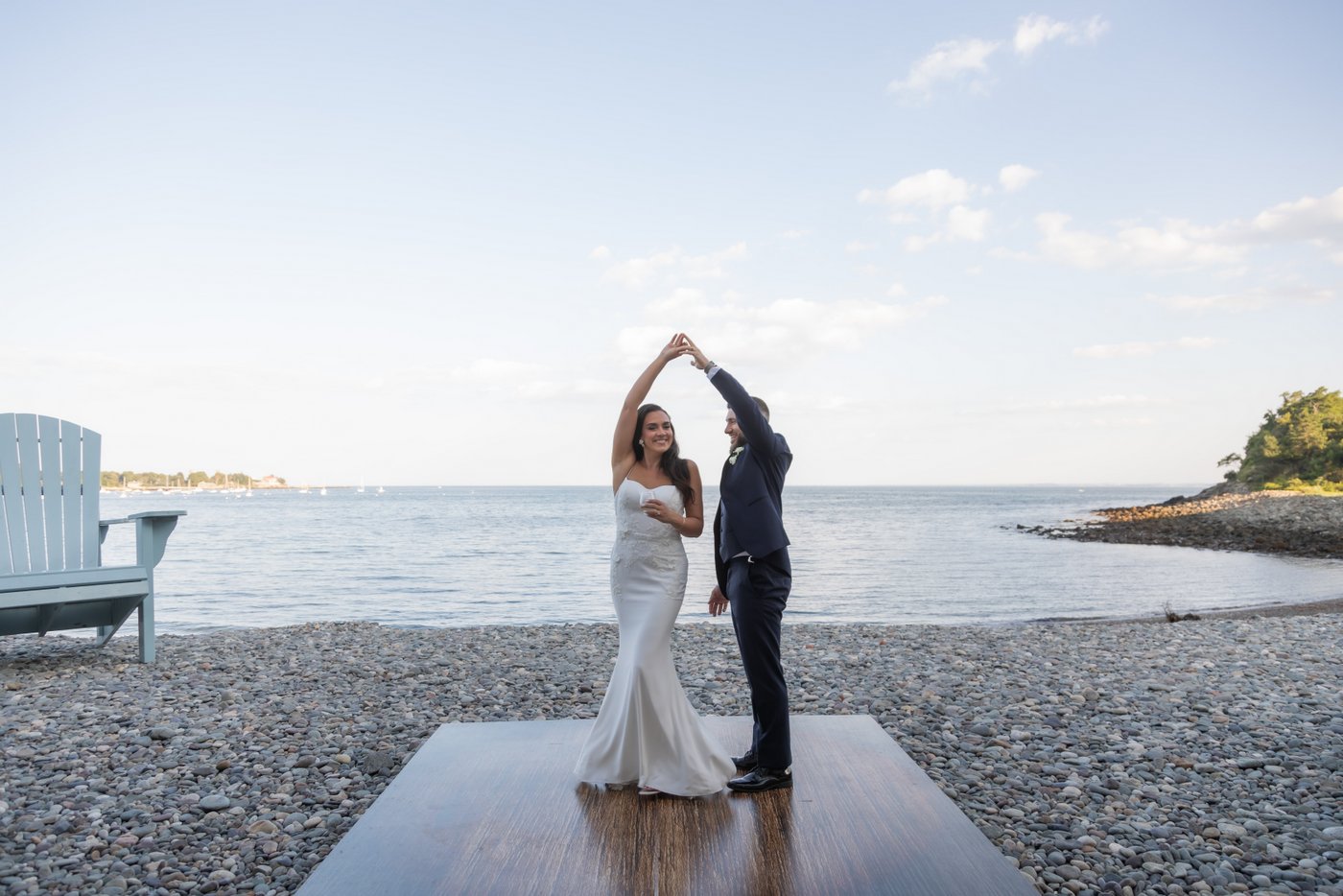 The groom twirls the bride on the beach during their Oceanview of Nahant wedding