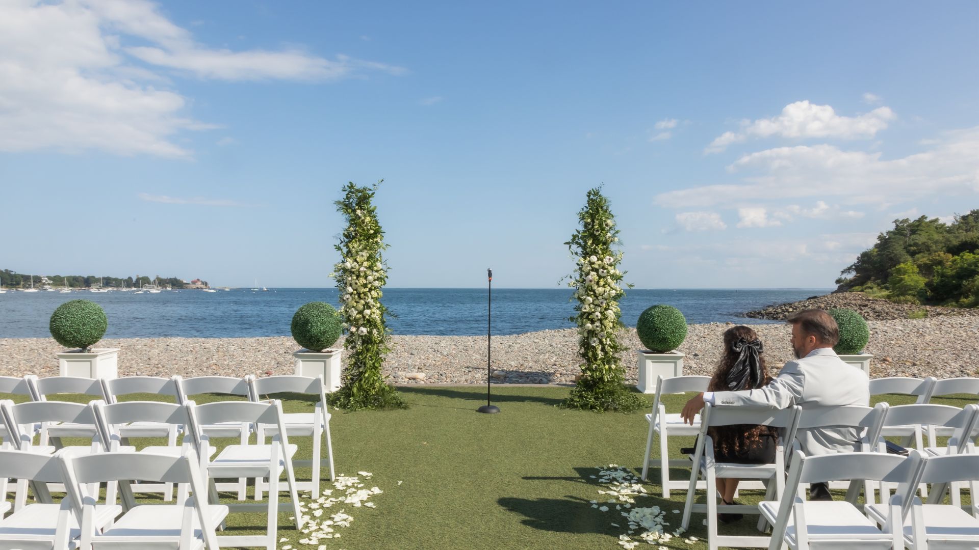 The ceremony setup with white chairs and floral pillars at Oceanview of Nahant before wedding guests arrive