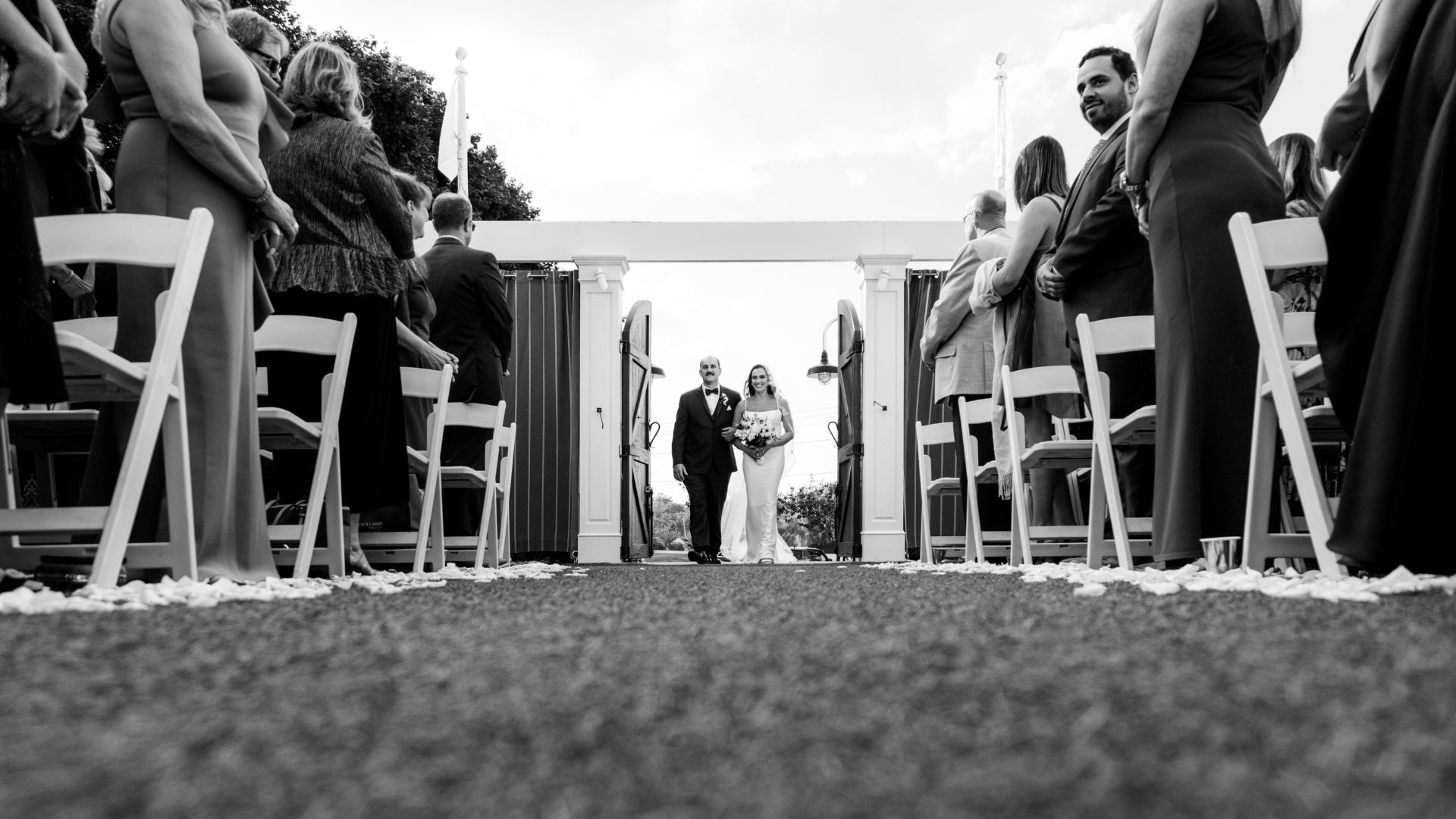 A dramatic black and white photograph of the bride and her father walking down the aisle toward the alter during an Oceanview of Nahant wedding