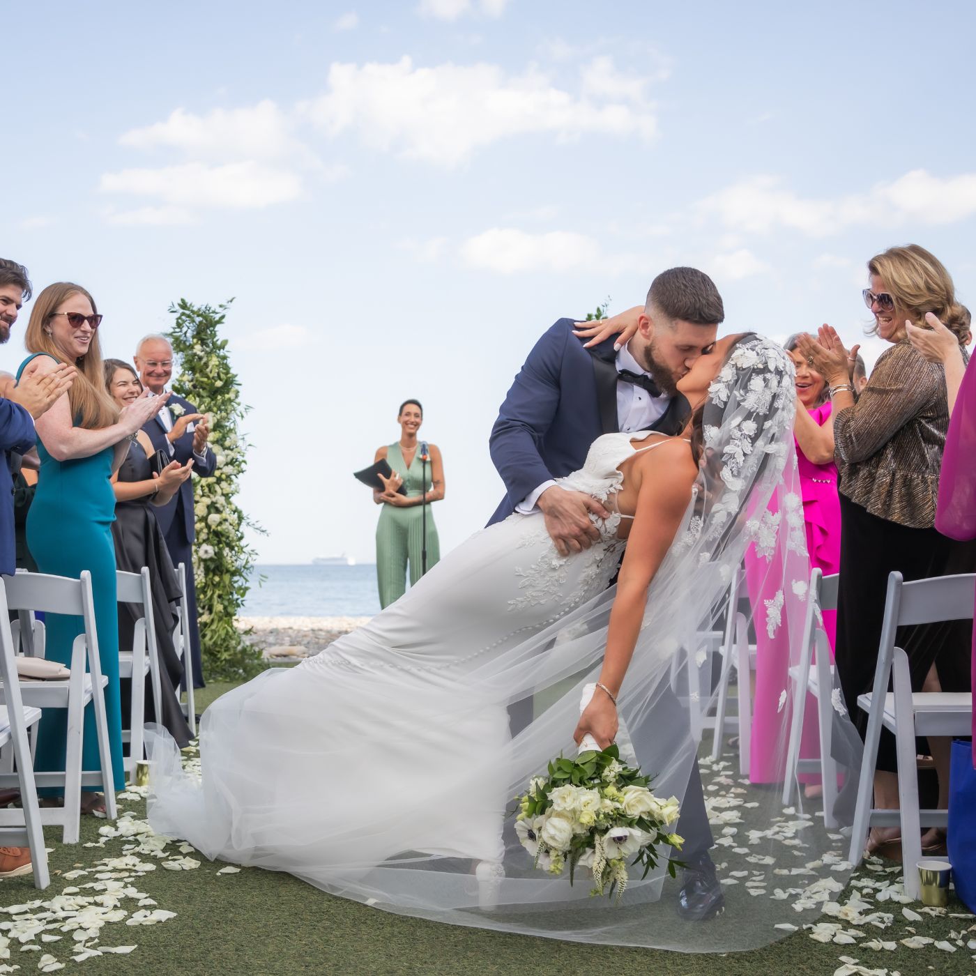 The groom dips the bride in the aisle at the conclusion of their wedding ceremony at Oceanview of Nahant, square crop.