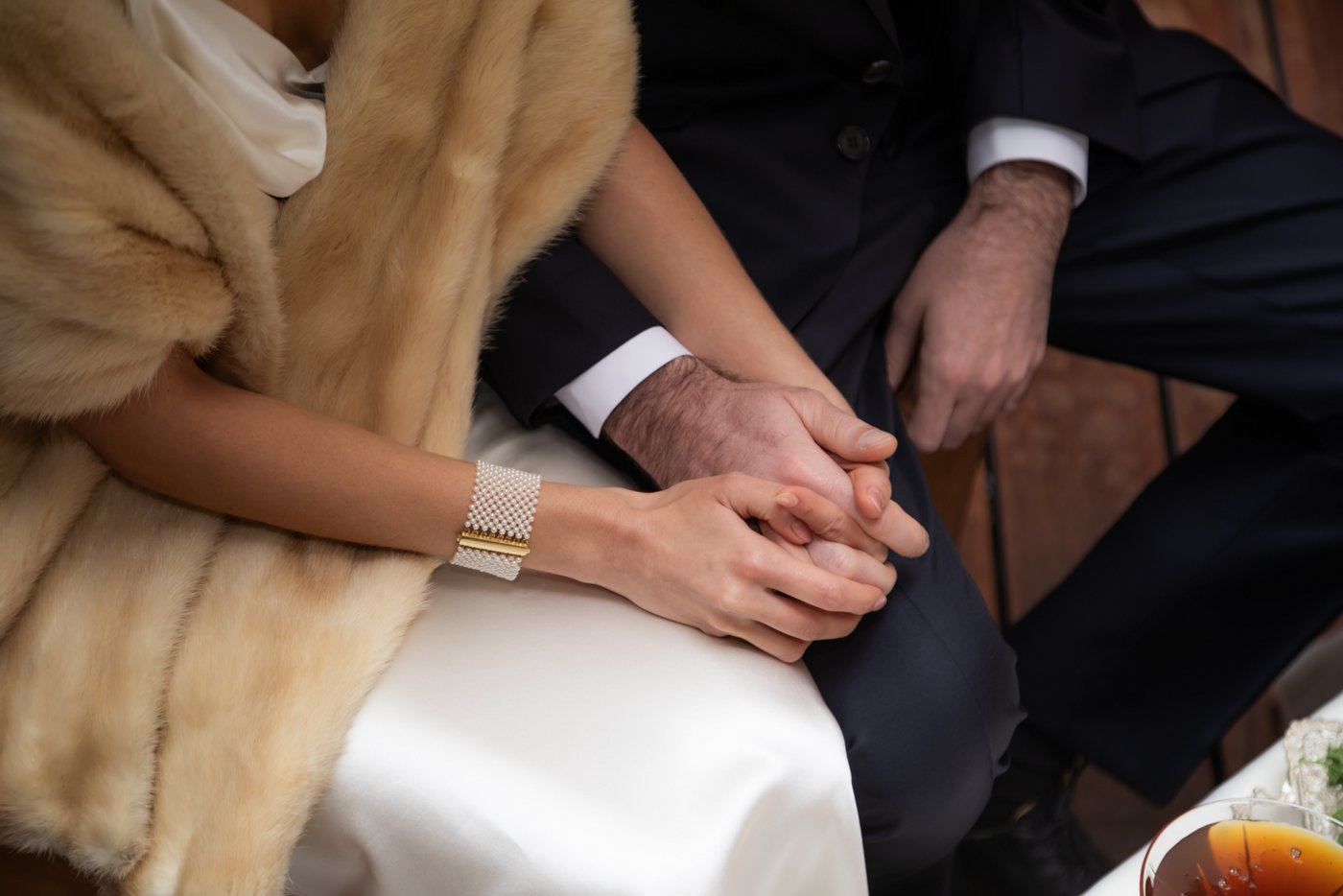 The bride and groom hold hands sitting under the canopy at the altar.