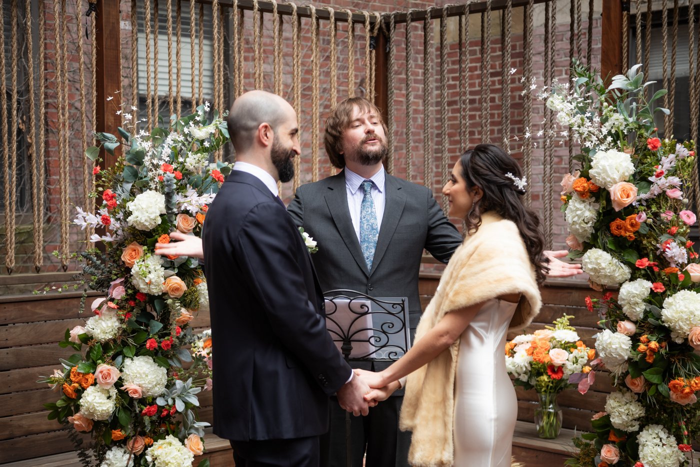 Bride and groom hold hands as the officiant pronounces them married during their SRV Boston wedding.