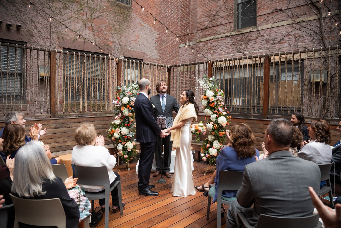 Bride and groom hold hands as the officiant pronounces them married during their SRV Boston wedding.