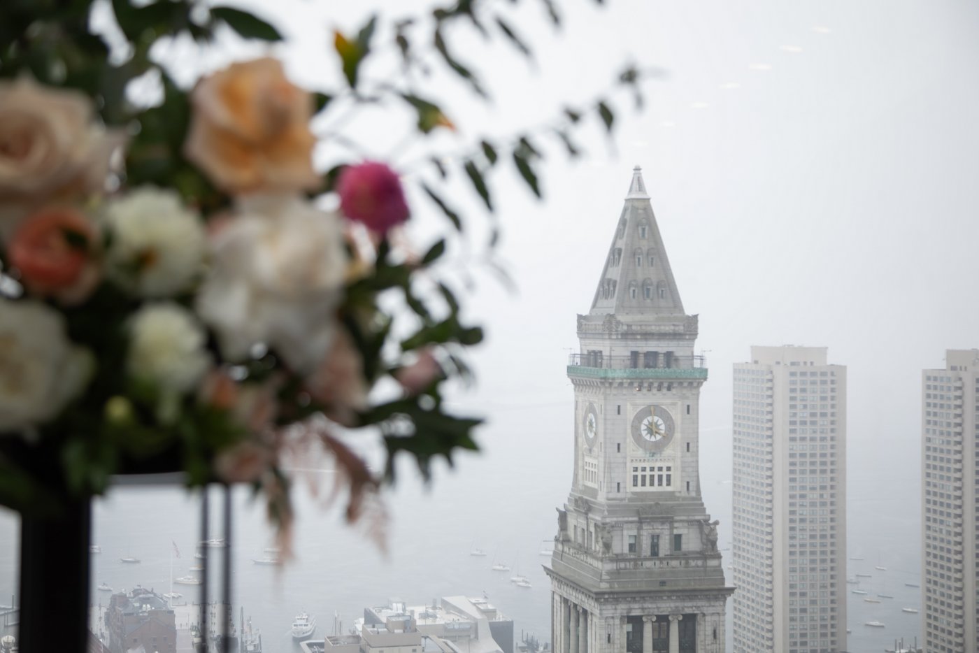 A shot of the Clock Tower of the Custom House with the wedding florals in the foreground at a State Room Boston wedding