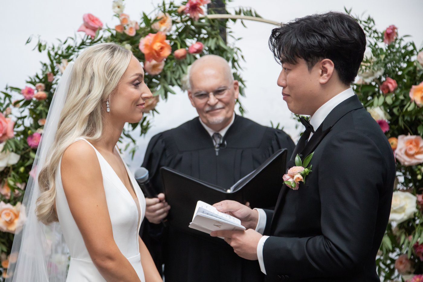 The groom reading his vows as the bride looks on and smiles during their State Room Boston wedding ceremony.