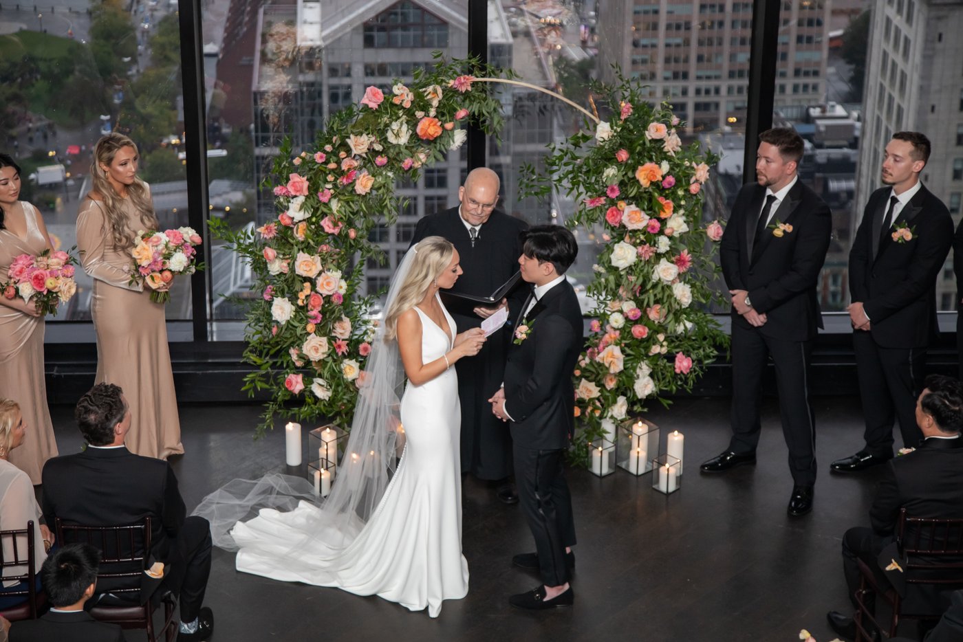 The bride reads her vows as the groom, the officiant, and the bridal party watch her at a State Room Boston wedding