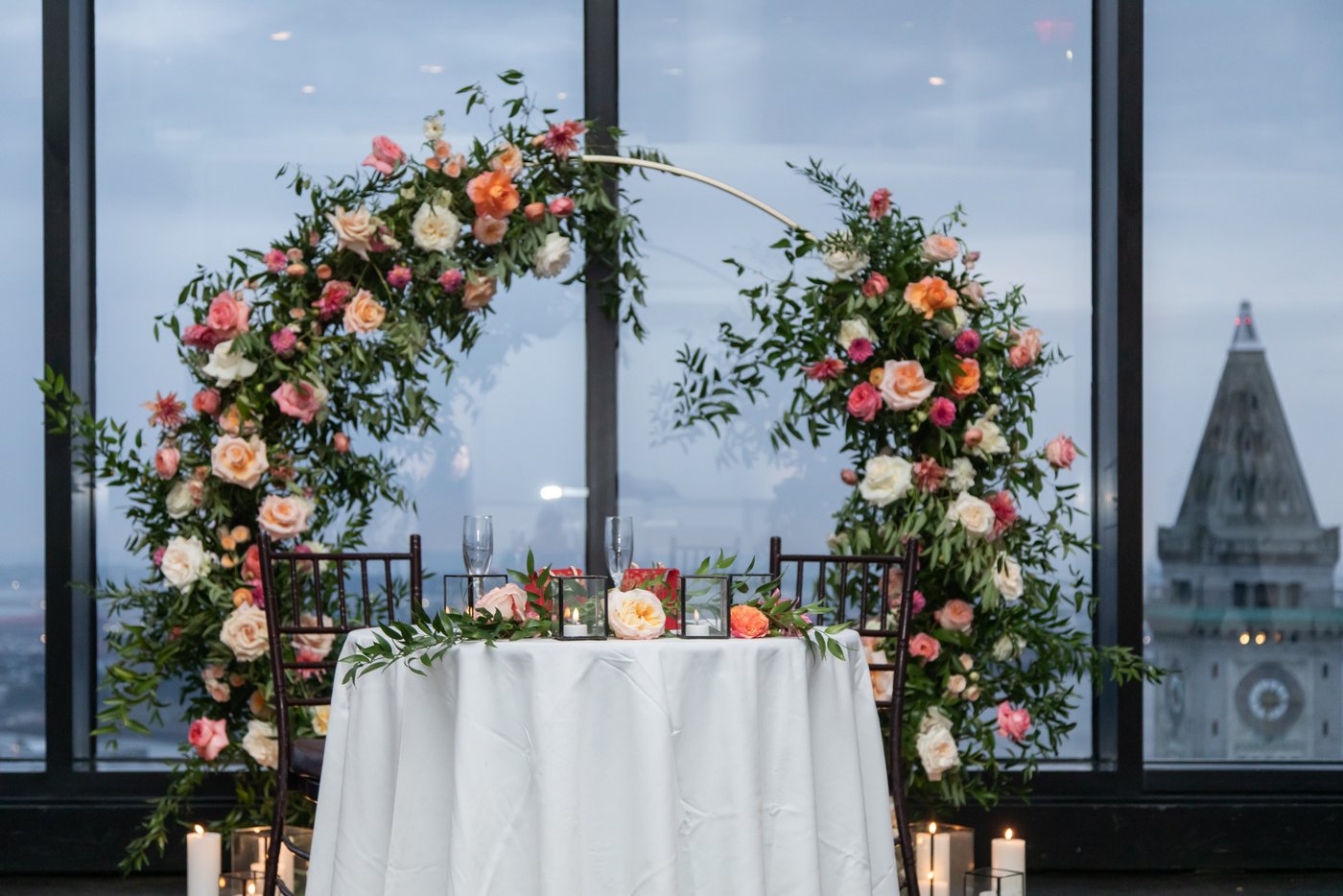 The sweetheart table with the Boston skyline behind it, photographed at the blue hour during a State Room Boston wedding