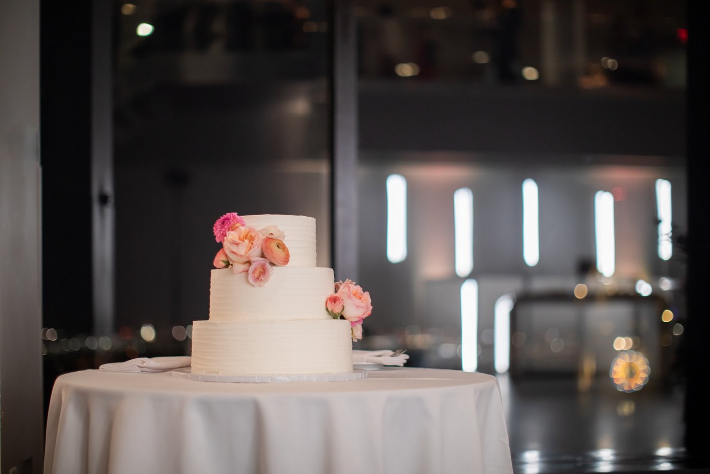 The wedding cake with its three tiers and pink roses at a State Room Boston wedding
