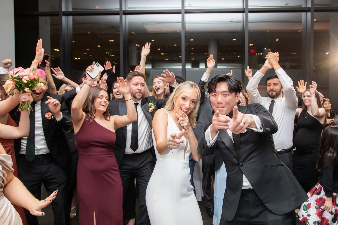 The bride and groom point at the camera and strike a pose as they dance during State Room Boston wedding reception grand entrance